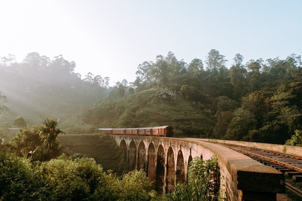 Train crossing the Nine Arch Bridge on a railway track in Ella, Sri Lanka, surrounded by lush mountain scenery