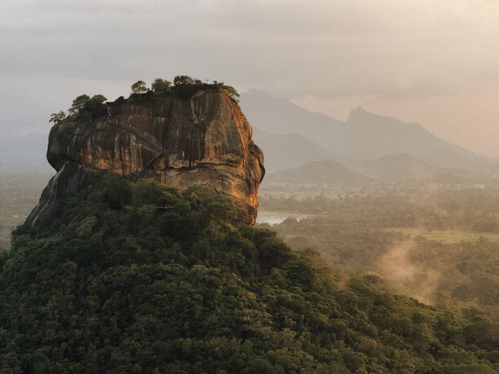 Stunning aerial view of Sigiriya Rock, lush landscape, and distant mountains in Sri Lanka.