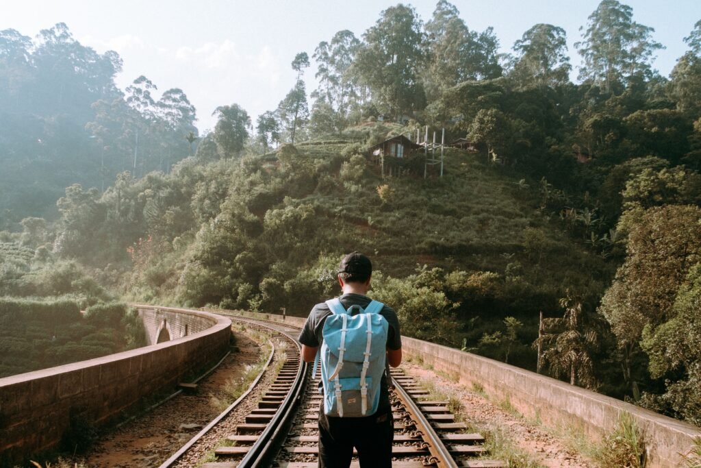 A solitary backpacker stands on the nine arch brindge train tracks amidst lush greenery in Ella, Sri Lanka.