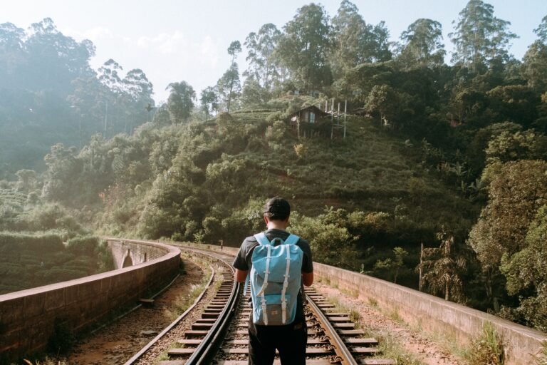 A solitary backpacker stands on the nine arch brindge train tracks amidst lush greenery in Ella, Sri Lanka.